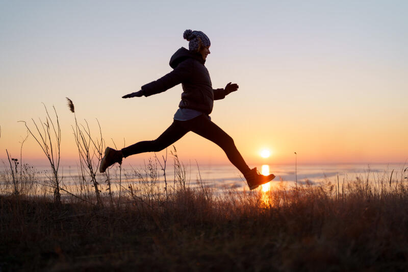 Woman jumping on a beach at sunset